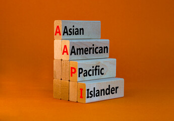 AAPI symbol. Abbreviation AAPI asian american pacific islander on wooden blocks. Beautiful orange background. Copy space. Business and AAPI asian american pacific islander concept.
