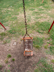 Broken kids swing with metal chain and tube supports on ground and grass front view