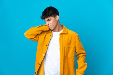 Young man over isolated blue background with neckache