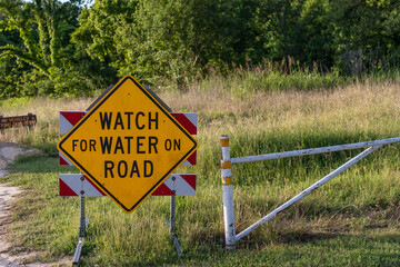 Sign reading "Watch for Water on Road" sign due to flooding caused by sea level rise and climate change