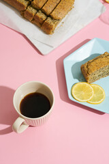 lemon poppy cupcake on a blue minimalistic plate on a pink background. Composition with hard shadows from the sun