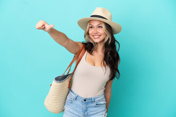 Teenager Russian girl with pamel and beach bag isolated on blue background giving a thumbs up gesture