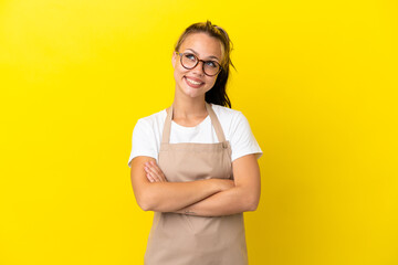 Restaurant waiter Russian girl isolated on yellow background looking up while smiling