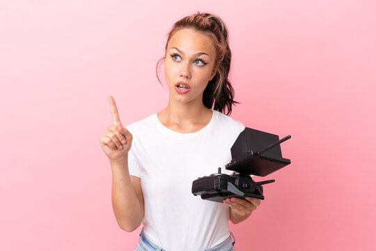 Teenager Russian girl holding a drone remote control isolated on pink background thinking an idea pointing the finger up