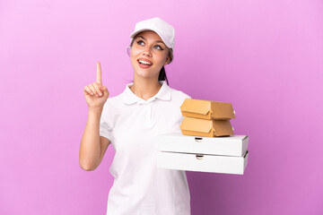 Pizza delivery Russian girl with work uniform picking up pizza boxes and burgers isolated on purple...