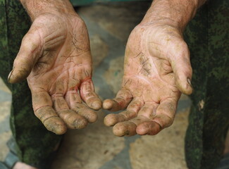 The hands of a senior handyman man, with calluses and cracks. Agricultural manual labor.