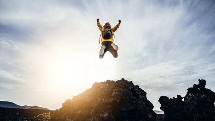 Happy man with open arms jumping on the top of mountain - Hiker with backpack celebrating success...