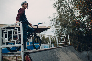 Professional young sportsman cyclist with bmx bike at skatepark