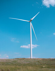 Fototapeta premium windmill on the background of the cloudy blue sky. Concept of alternative energy production from wind. Modern windmill with full-length blades. High quality photo