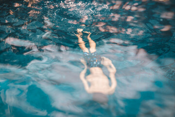 8 years old faceless boy swimming in a pool