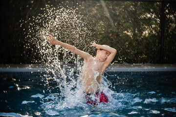 happy 8 years old boy having fun in a swimming pool during summer