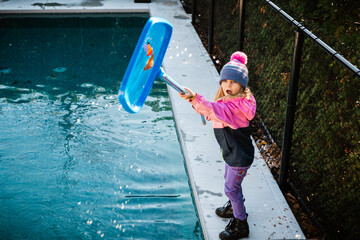 5 years old girl cleaning the swimming pool during fall