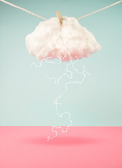 Lightning strikes from cloud hanging on a rope. On blue and pink trendy background. Minimal...
