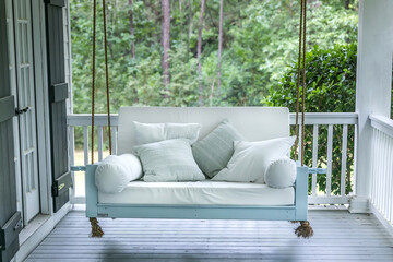 A luxurious and classic outdoor bed swing painted a seafoam green with white deep cushions - obrazy, fototapety, plakaty