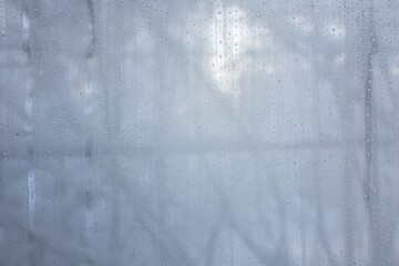 water drops on the fogged glass in the house against the background of winter