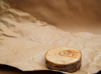 A round slice of wood lies on crumpled beige kraft paper. Wrapping paper for parcels and gifts.