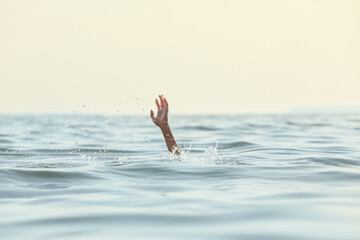 Drowning woman reaching for help in sea