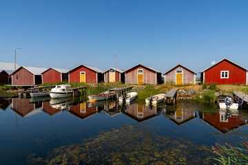 colorful fishing cottages and boats reflected in the water under a blue sky