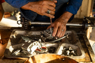 A man, who works as a mechanic, skillfully fixes the carburetor of a boat engine in his workshop