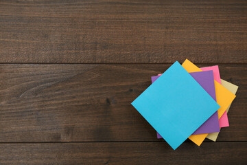 Stack of colorful stickers on wooden table, top view. Space for text