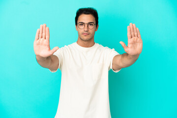 Naklejka premium Caucasian handsome man over isolated blue background making stop gesture and disappointed