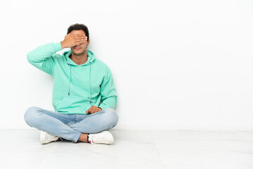 Caucasian handsome man sitting on the floor covering eyes by hands. Do not want to see something