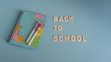 Back to school concept. 
Education in COVID-19 pandemic. Medical mask and school supplies on a green  background