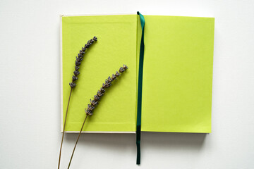 notebook with space for text, green paper, green bookmark, lavender decoration, white background, canvas texture, top photo