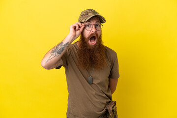 Redhead Military man with dog tag isolated on yellow background with glasses and surprised