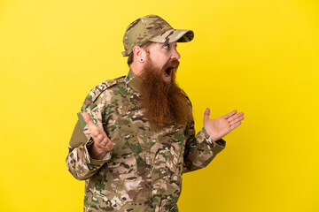 Military Redhead man over isolated on yellow background with surprise facial expression