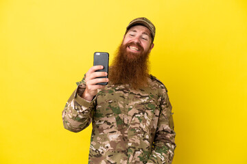 Military Redhead man over isolated on yellow background making a selfie