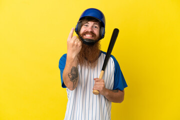 Redhead baseball player man with helmet and bat isolated on yellow background doing coming gesture