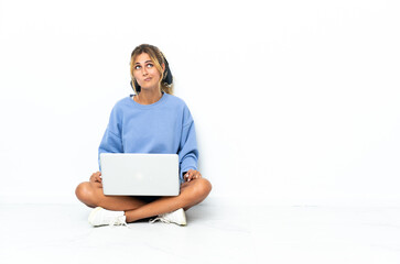 Young blonde Uruguayan girl with the laptop isolated on white background and looking up