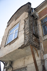Fototapeta na wymiar old dangerous cracked brick wooden and metal structures of a residential building on a city street