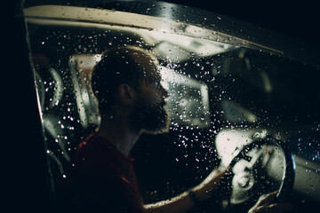 Obraz na płótnie Canvas Man driver sits at steering wheel of car at night.