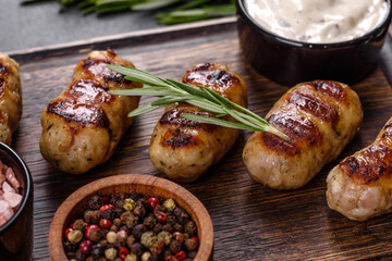 Grilled sausage with the addition of herbs and vegetables on the dark background