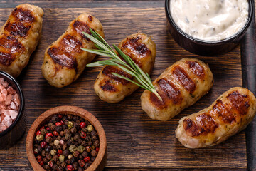 Grilled sausage with the addition of herbs and vegetables on the dark background