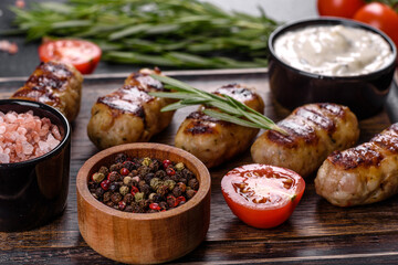 Grilled sausage with the addition of herbs and vegetables on the dark background