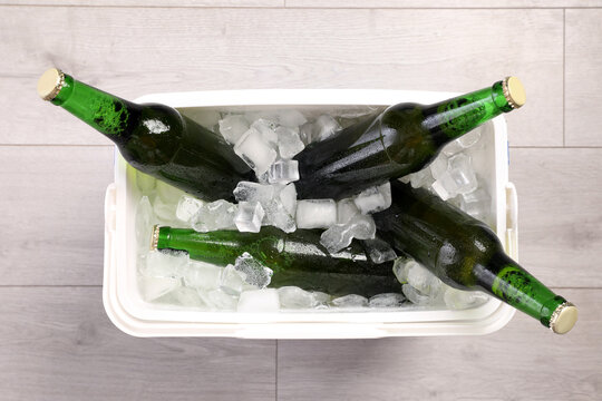 Plastic Cool Box With Ice Cubes And Beer On Wooden Floor, Top View