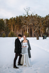 The groom is holding a wedding cake in his hands, the bride is standing next to him.