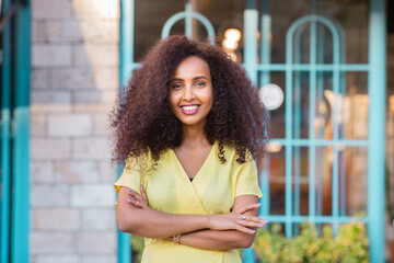 Happy Afro Black young woman have a confident smile is posing in front of her shop or business with her curly hair. Copy space includes.