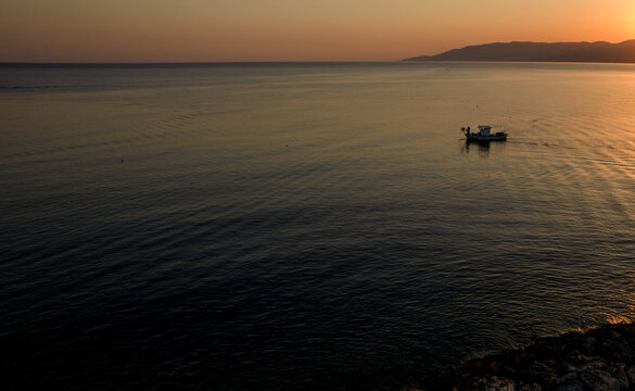 Aerial drone view of fishing boat sailing in the sea at sunrise. Latsi Paphos Cyprus