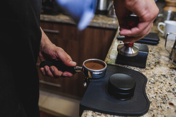 Fototapeta na wymiar barista prensando café recién molido en el porta filtro