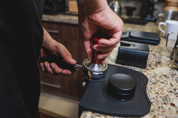 barista prensando café recién molido en el porta filtro