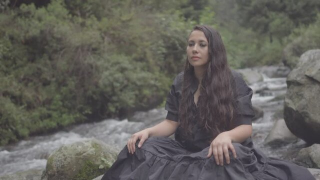 Bella y joven mujer latina contemplando y disfrutando del r&iacute;o en el bosque 
