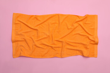 Crumpled orange beach towel on pink background, top view