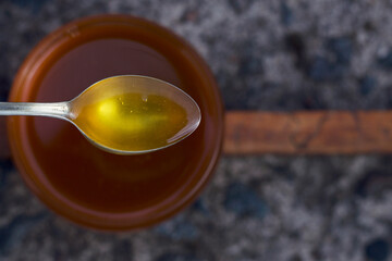 Fresh summer honey in a spoon under the jar flat lay.