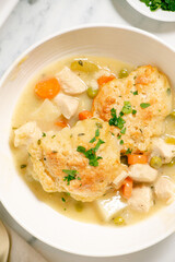Fototapeta na wymiar Homemade chicken and dumplings with carrots, peas and potatoes in a white baking dish