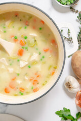 Homemade chicken and dumplings with carrots, peas and potatoes in a white baking dish