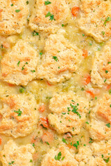 Homemade chicken and dumplings with carrots, peas and potatoes in a white baking dish